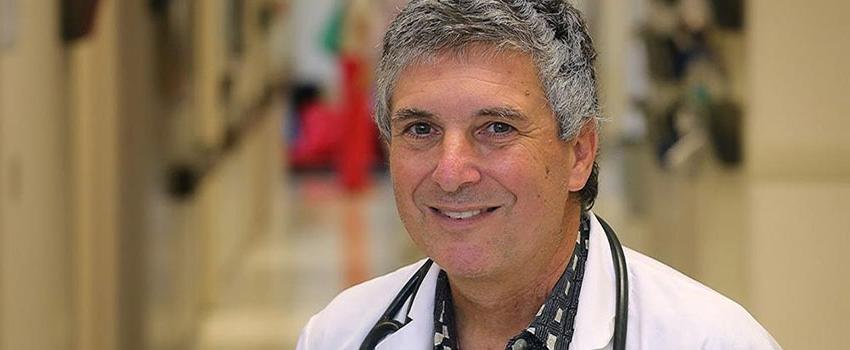 Dr. Perkins in white coat with stethoscope around his neck.